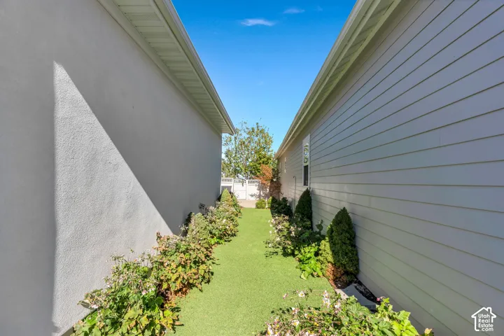 Stucco exterior with siding, artificial turf pathway, and established landscaping