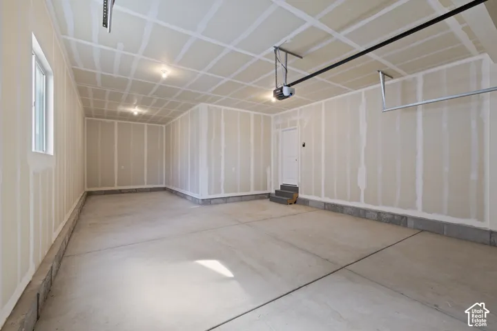 Spacious garage featuring concrete flooring, a large window, recessed lighting, a built-in storage rack, and an automatic garage door opener