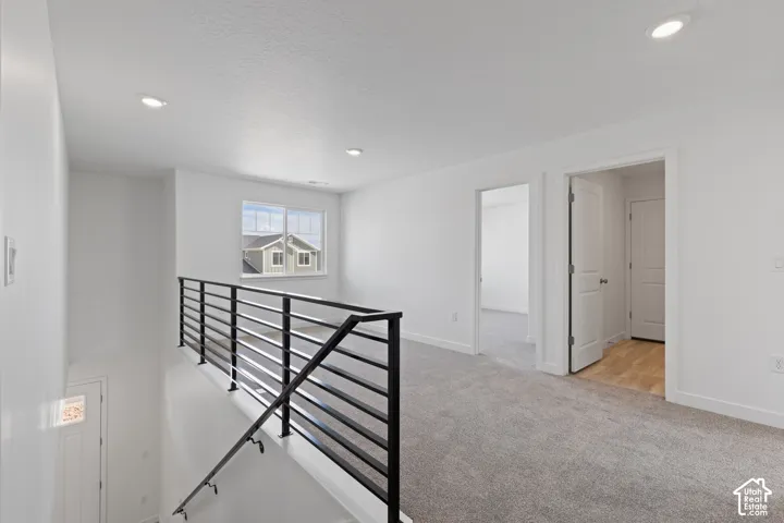 Upper-level landing featuring recessed lighting, a window, and a contemporary black metal railing