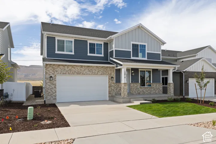 Two-story residence featuring a covered front porch, an attached two-car garage, and a combination of brick and siding exterior finishes