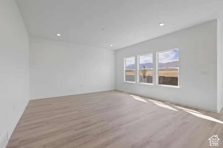 Recessed lighting, light wood-finish flooring, and multiple windows with a mountain backdrop