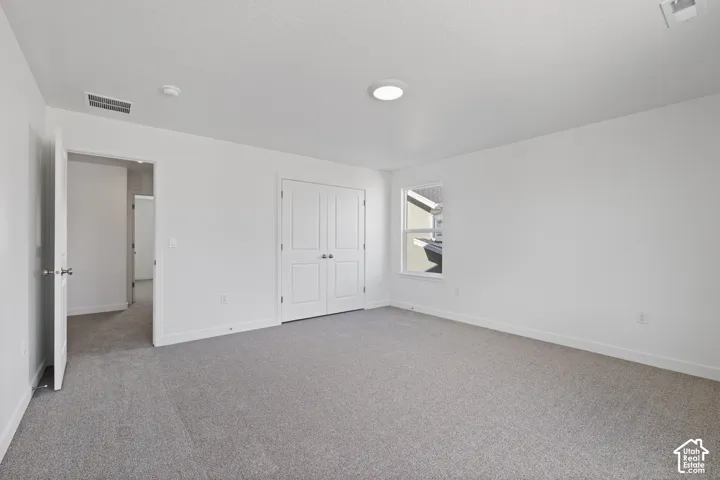 Bright interior space featuring light gray carpet flooring, white walls, and a ceiling-mounted light fixture