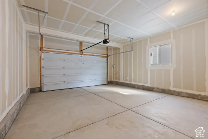 Spacious garage with a concrete floor, built-in window, and overhead garage door opener