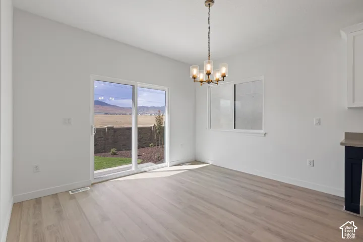 Light-tone wood-finish flooring, white walls, and a contemporary chandelier
