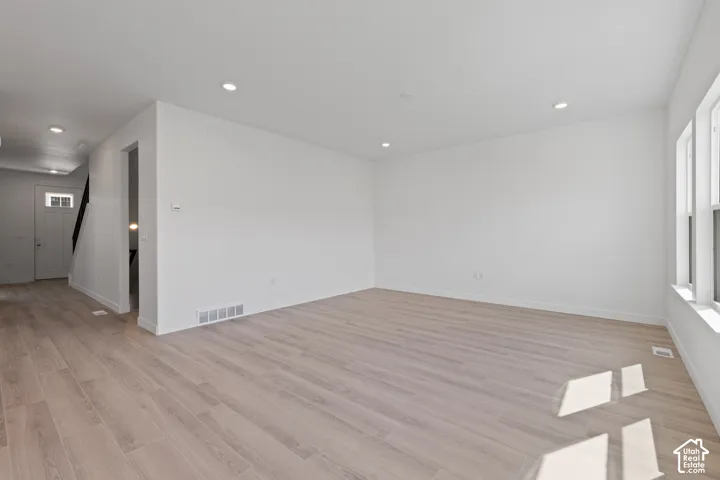 Spacious room featuring wood-finish flooring, recessed lighting, and multiple windows