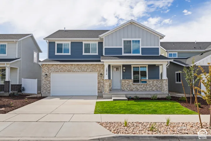 Two-story residence featuring a covered entry, attached two-car garage, and a combination of horizontal siding and stone veneer