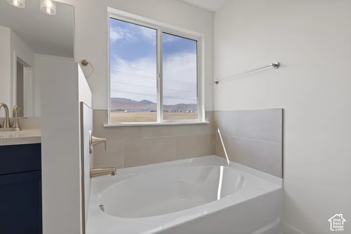 Soaking tub with tile surround, brushed nickel fixtures, and ample natural light from a large window