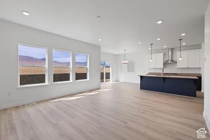 Recessed lighting throughout, wood-finish flooring, kitchen island with seating, stainless steel appliances, and ceiling-mounted light fixtures