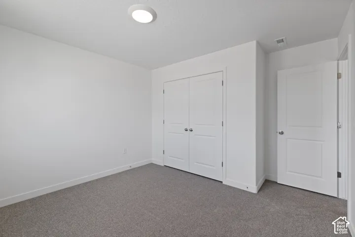 Recessed ceiling light fixture, white walls, gray carpet flooring, and white paneled doors