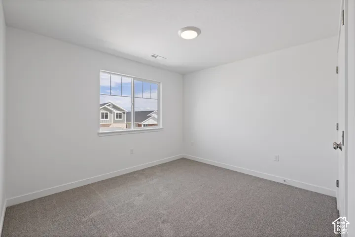 Neutral wall tones, gray carpet flooring, flush mount ceiling lighting, and a single window with white trim
