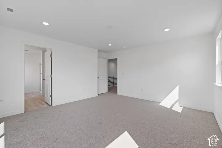 Recessed ceiling lighting, light-toned carpeting, white walls, and a window
