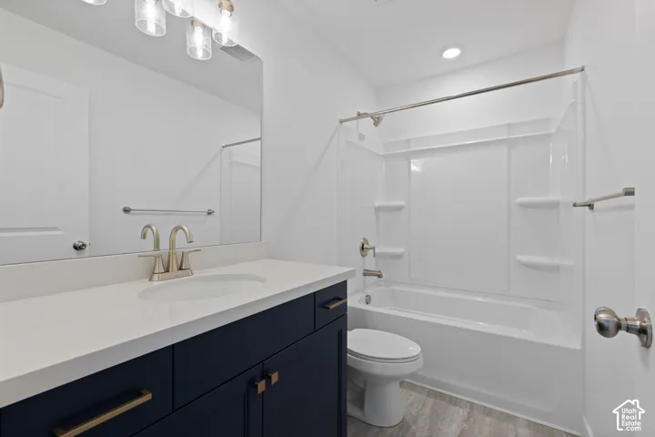 Vanity with a white countertop and dark cabinetry, undermount sink with a two-handle faucet, full-width mirror, and a built-in tub with a shower