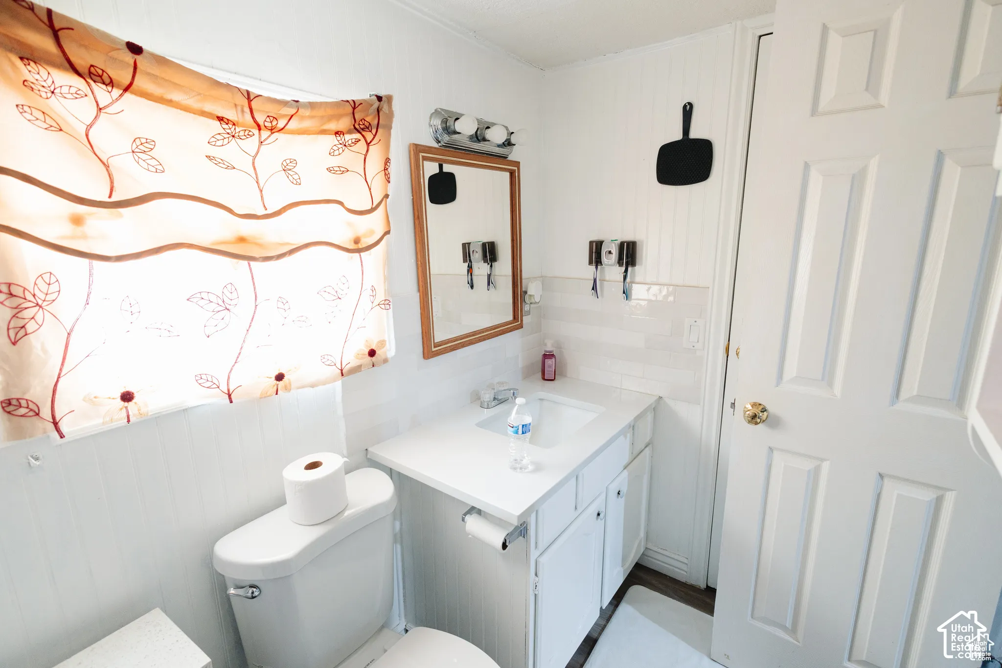 Vanity with an integrated sink and cabinet storage, featuring a tiled backsplash and wood-framed mirror