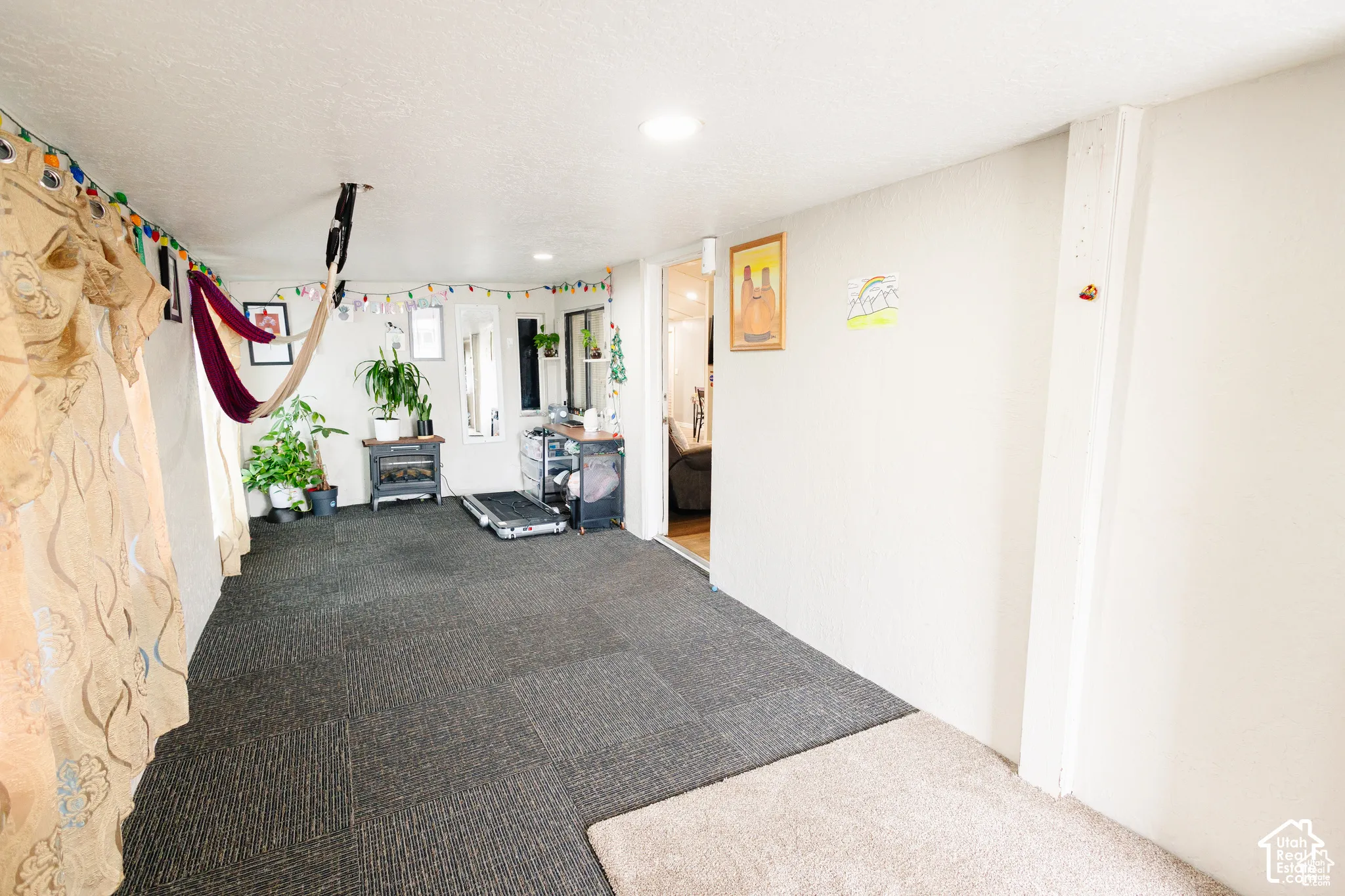 Spacious room featuring neutral wall tones, recessed lighting, and a soft gray carpet tile flooring