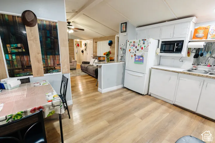 Kitchen featuring wood-finish flooring, white cabinetry, integrated microwave, and a double-basin stainless steel sink