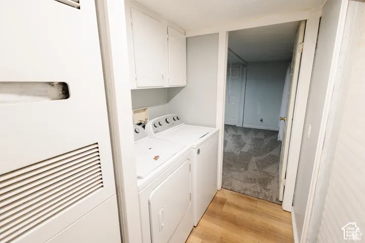 Laundry area with wood-finish flooring, white cabinetry, and a utility closet