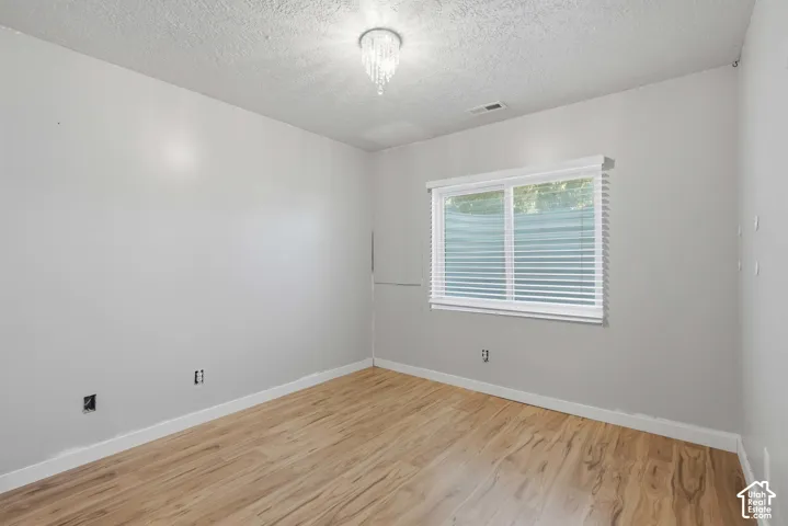 Wood-finish flooring, white window blinds, white trim, and a ceiling-mounted light fixture