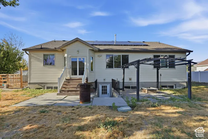Rear exterior with siding, a concrete patio, a pergola structure, and a basement entrance