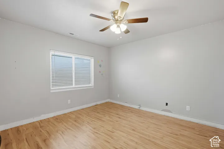 Wood-finish flooring with neutral wall tones, a ceiling fan with integrated lighting, and a window with horizontal blinds