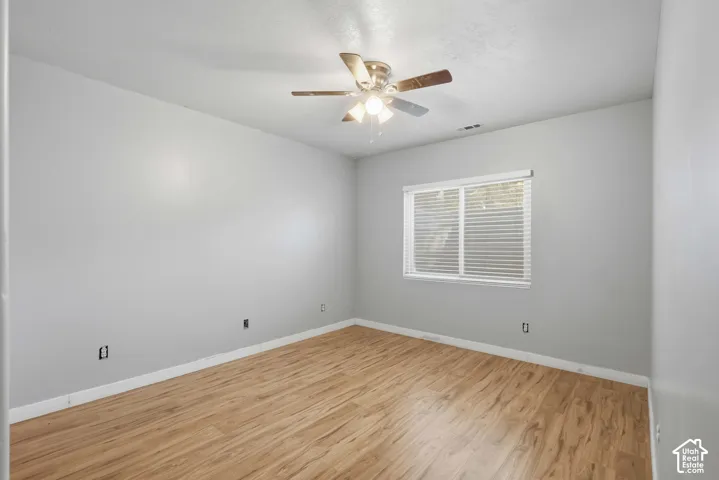 Wood-finish flooring, ceiling fan with integrated lighting, and a window with horizontal blinds