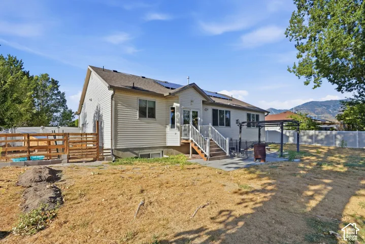 White vinyl siding exterior with multiple windows, upper-level deck, and a shaded patio area
