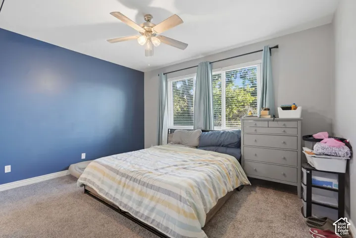 Room featuring a ceiling fan with integrated lighting, two windows with blinds, and carpeted flooring