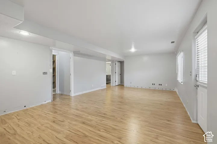 Spacious room featuring wood-finish flooring, recessed lighting, and multiple entryways