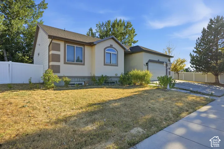 Stucco and siding exterior, arched window detail, attached garage, concrete driveway, white privacy fencing