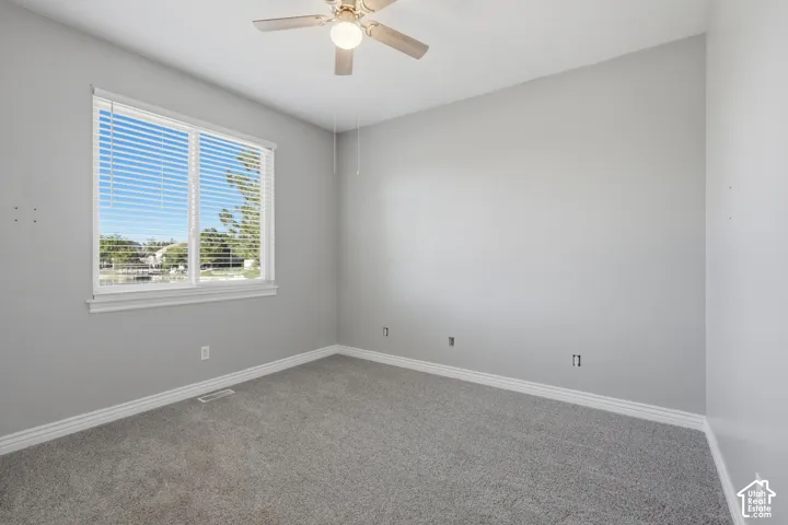 Recessed window with white blinds, neutral gray wall tones, plush gray carpet, and a ceiling fan with integrated lighting