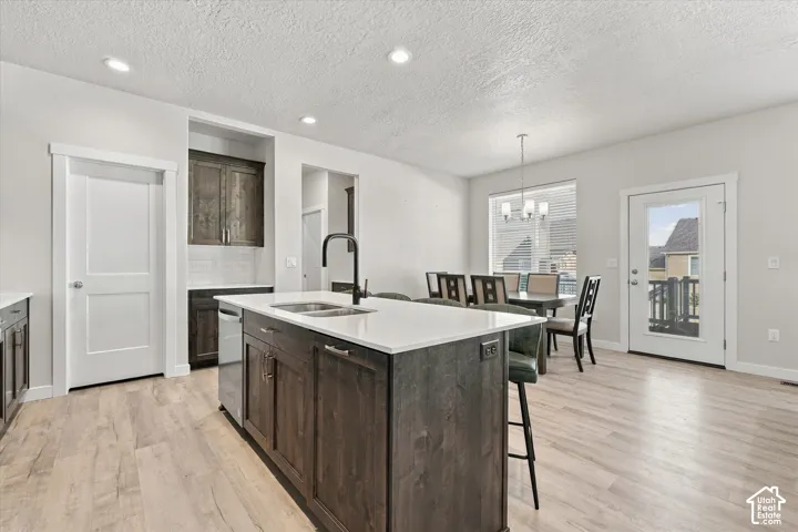 Kitchen island with integrated sink, stainless steel dishwasher, and dark wood-finish cabinetry