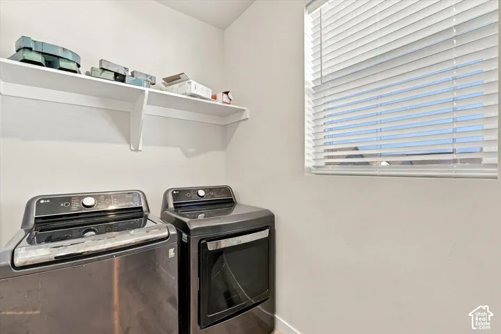 Laundry area featuring a window with blinds and an overhead storage shelf