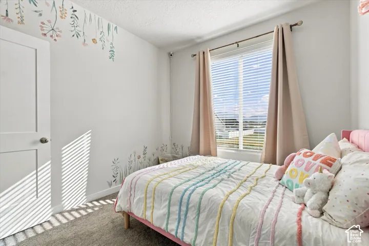 White painted walls, single window with blinds, light-colored curtains, and gray carpeted flooring