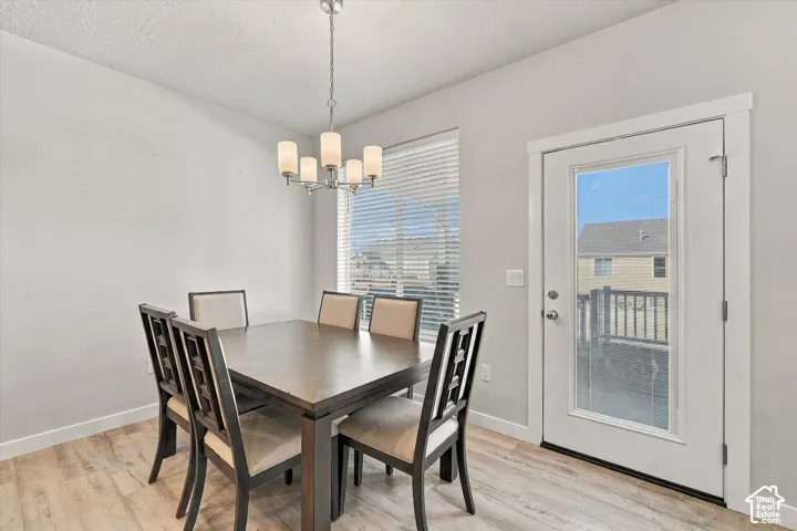Wood-finish flooring, white walls, and a multi-light chandelier