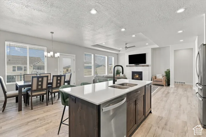 Expansive kitchen island with a double basin sink, stainless steel dishwasher, and light-toned countertops