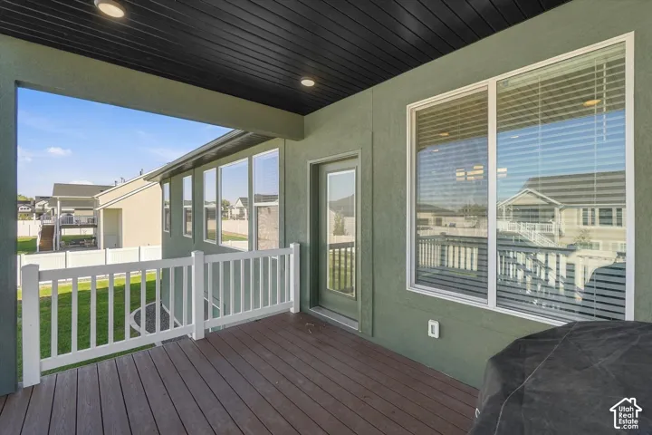 Covered deck featuring wood-finish flooring, white railing, recessed lighting, and a glass-paneled door
