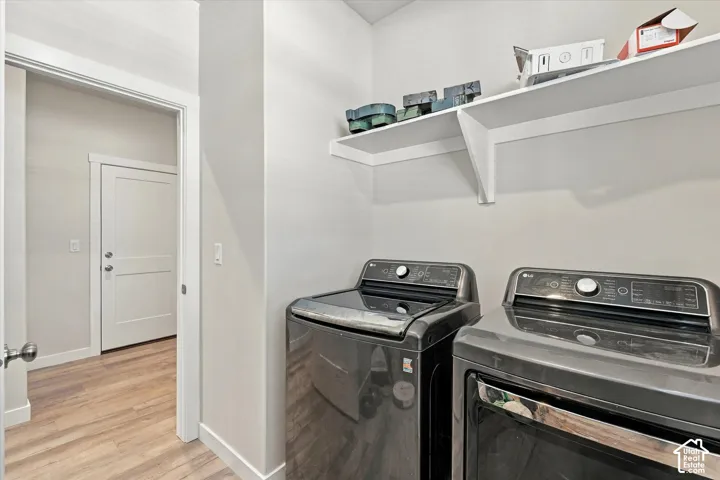 Laundry area featuring wood-finish flooring and wall-mounted shelving