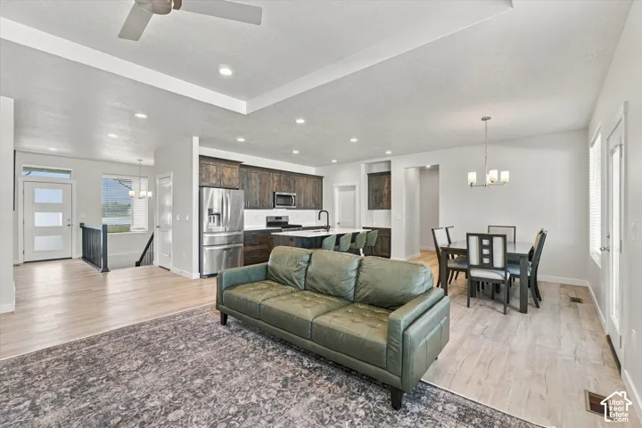 Recessed lighting, light wood-finish flooring, dark wood-finish cabinetry, stainless steel appliances, and a tray ceiling