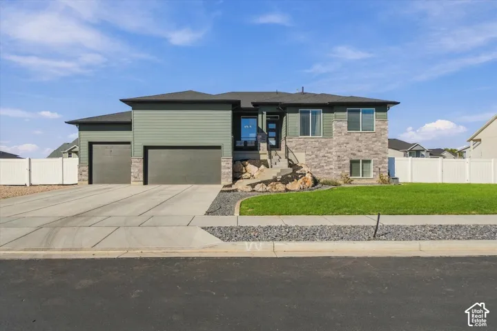 Split-level exterior with a two-car garage, stone and siding facade, and a concrete driveway