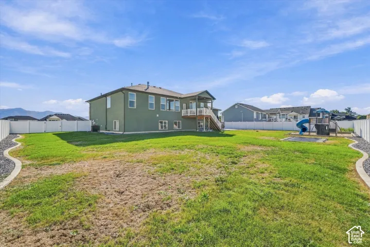 Expansive backyard with a green lawn, white privacy fencing, and a built-in play structure