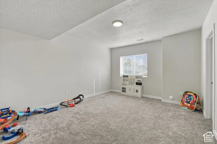 Carpeted room with a single window featuring horizontal blinds, recessed ceiling lighting, and a white interior door