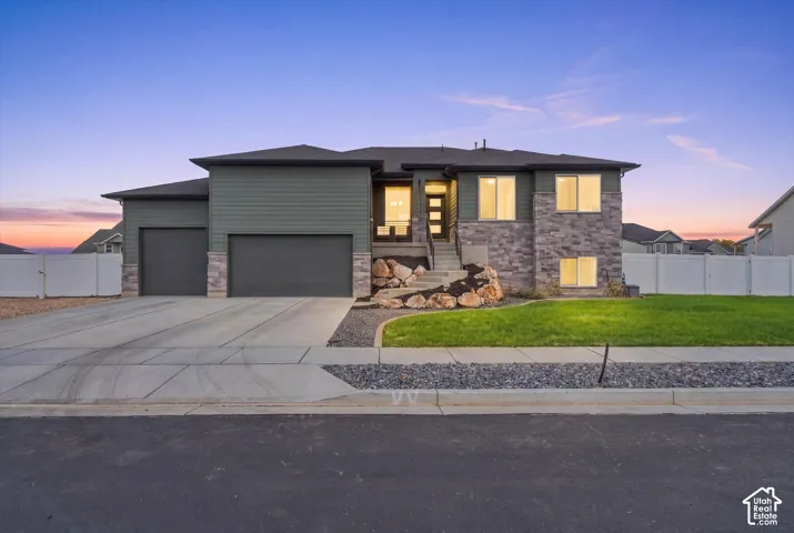 Contemporary exterior featuring stone accents, horizontal siding, a multi-pane entry door, and a two-car garage