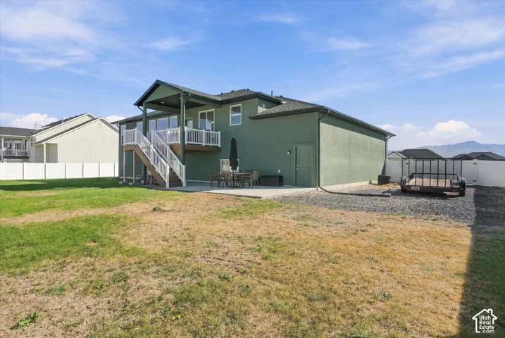 Green-toned exterior with a covered upper-level deck, white railing, and exterior staircase