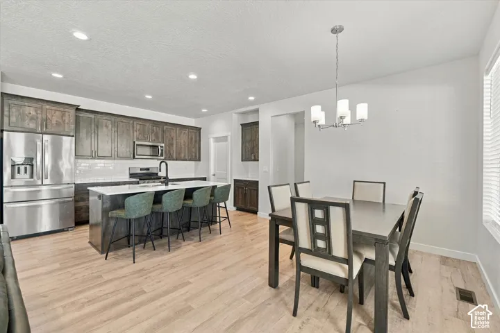 Spacious kitchen featuring wood-finish cabinetry, stainless steel appliances, a center island with seating, and subway tile backsplash