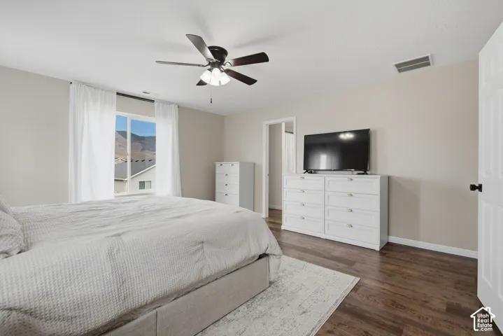 Wood-finish flooring with a neutral wall color, overhead ceiling fan, and window featuring mountain scenery