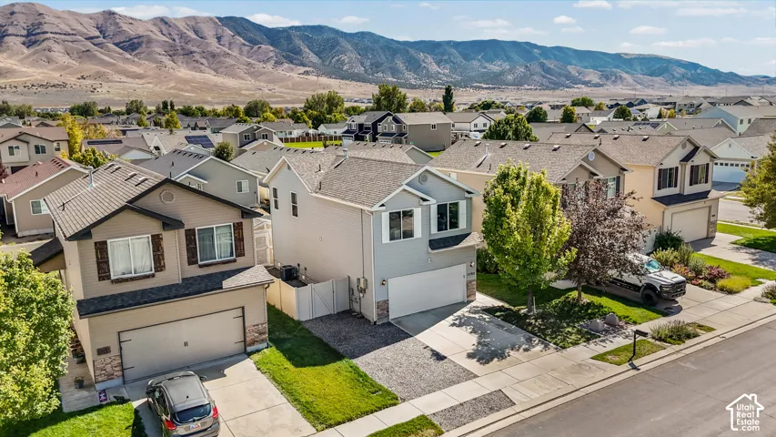 Two-story residential architecture with attached garages, surrounded by neighboring properties, with a prominent mountain backdrop