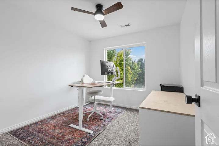 Recessed lighting, ceiling fan, large window, built-in desk, and grey carpet flooring