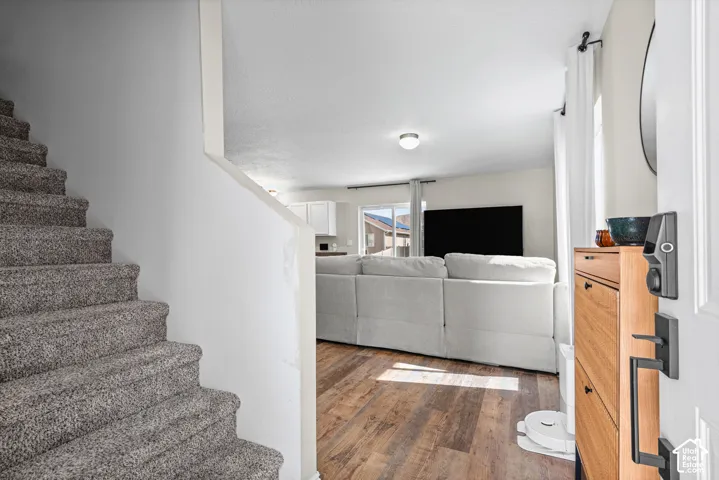 Wood-finish flooring, white walls, and a carpeted staircase