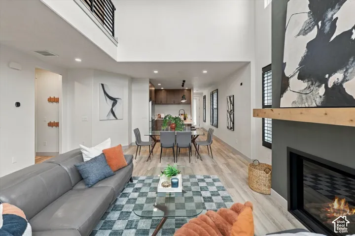 Great room featuring a fireplace with a wood mantle, high ceilings, and wood-finish flooring