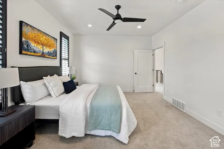 Spacious primary bedroom featuring neutral carpeting, recessed ceiling lighting, and a ceiling fan