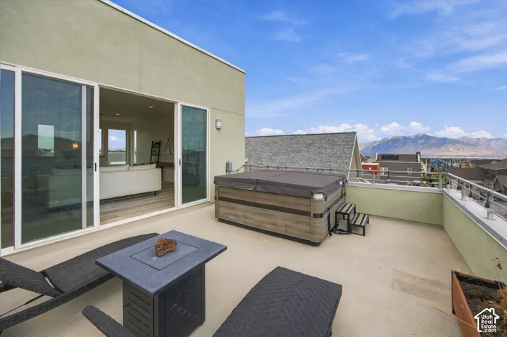 Expansive rooftop terrace featuring polished concrete flooring, built-in seating with storage, a fire pit table, and panoramic mountain vistas